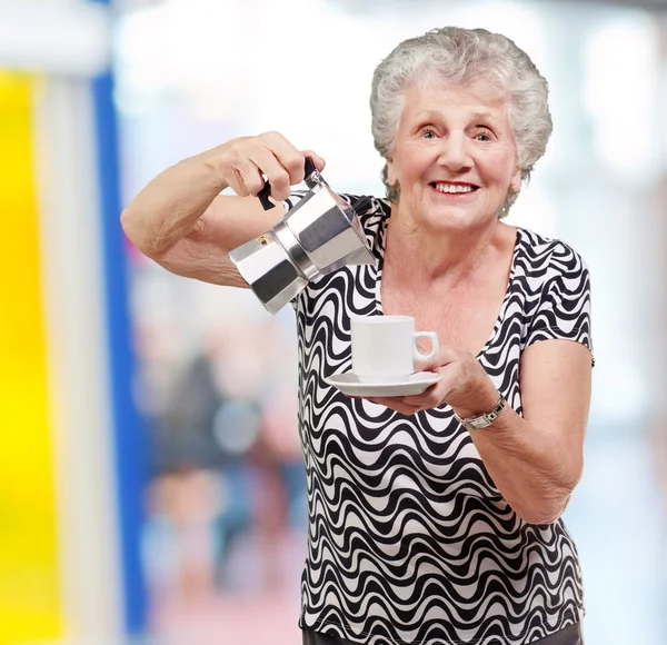 Portrait of a vitality senior woman serving a tea cup indoor — Stock Photo, Image