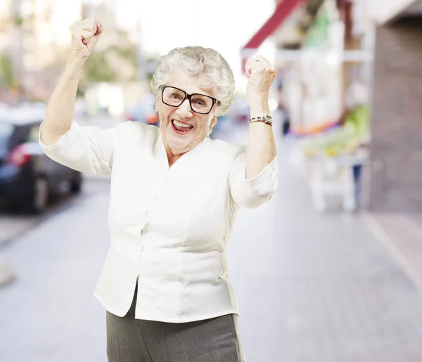 都市で陽気な年配の女性ジェスチャーの勝利の肖像画 — ストック写真
