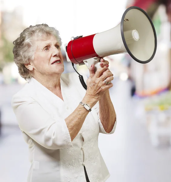 Portrait of senior woman holding megaphone at city — Stock Photo, Image