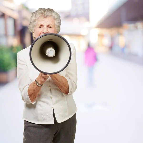 Портрет пожилой женщины, кричащей с мегафоном в городе — стоковое фото