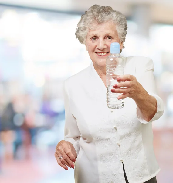 Portræt af en sund seniorkvinde med en vandflaske indendørs - Stock-foto