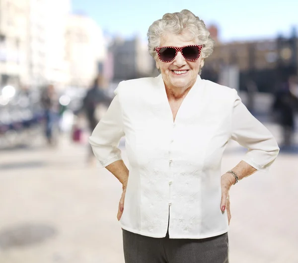 Портрет пожилой женщины, стоящей в солнечных очках в переполненном зале — стоковое фото