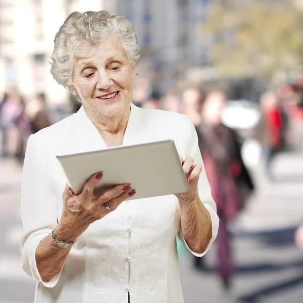 Porträtt av äldre kvinna röra digital tablet på city — Stockfoto