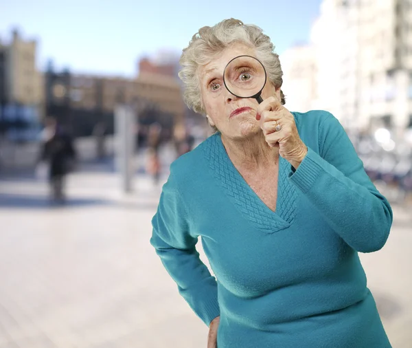 Retrato de mujer mayor mirando a través de una lupa agai —  Fotos de Stock