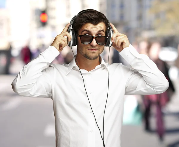 Portrait of young man listening to music using headphones at cro — Stock Photo, Image