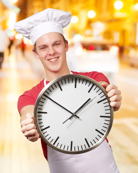 Portret młodej gotować człowieka posiadającego zegar w nocy miasto — Zdjęcie stockowe