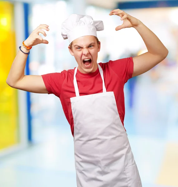 Porträt eines jungen Mannes mit Kochschürze, der aggressiv gestikuliert — Stockfoto