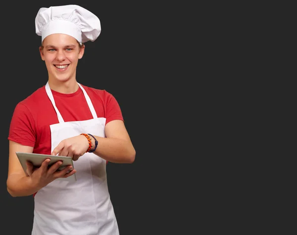 Jovem cozinheiro segurando um tablet digital — Fotografia de Stock