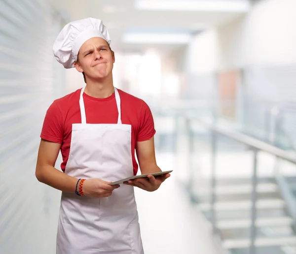 Portret van jonge kok man houden een digitale tablet en denken — Stockfoto