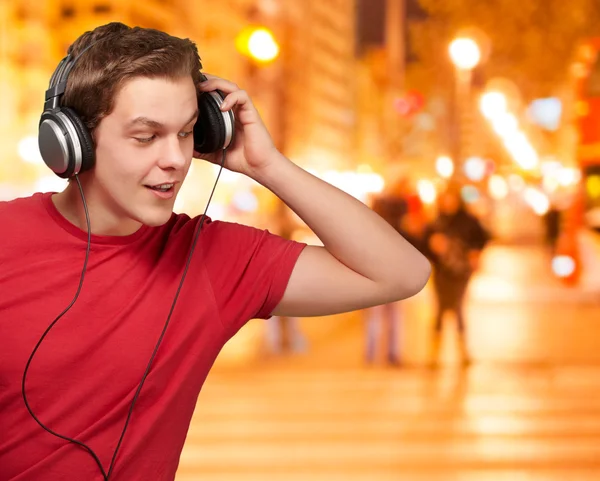Portret van een jonge man luisteren muziek bij nacht city — Stockfoto