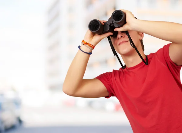 Retrato de un joven con prismáticos contra un edificio — Foto de Stock