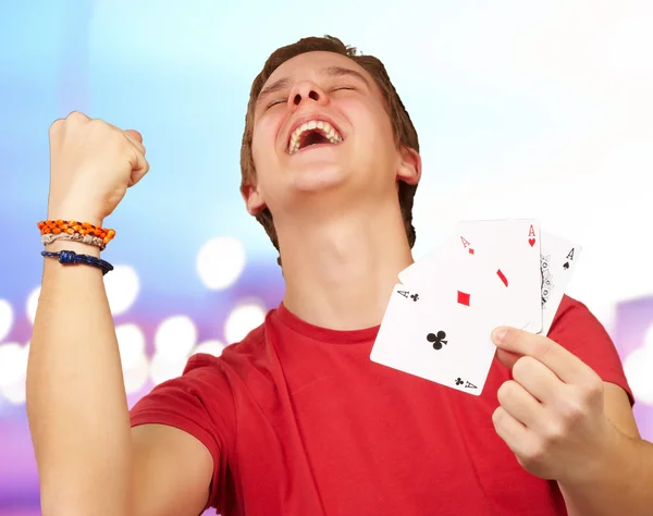 Портрет молодого чоловіка, який робить жест переможця, граючи в покер над — стокове фото