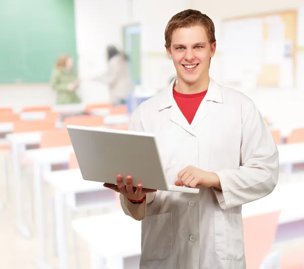 Portrait of young student holding laptop at classroom — Stock Photo, Image
