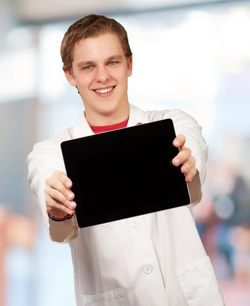 Портрет молодого человека, показывающего цифровой планшет в помещении — стоковое фото