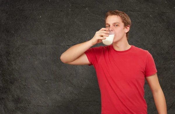 Portret młodzieńca, picie mleka o ścianę nieczysty — Zdjęcie stockowe