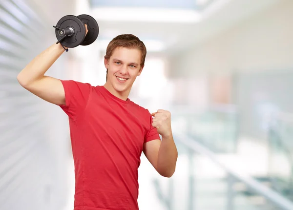 Młody człowiek robi fitness z wagi przy wejściu do budynku — Zdjęcie stockowe