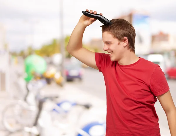 Portrait of young man cutting his hair at street — Stock Photo, Image