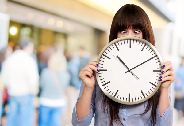 Mujer sosteniendo el reloj con ojos entrecerrados — Foto de Stock