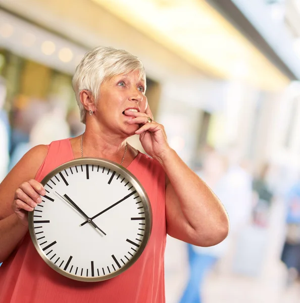 Starší žena drží hodiny a myšlení — Stock fotografie