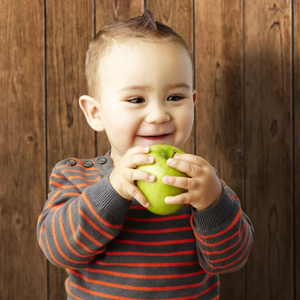 Portrait of funny kid holding green apple and smiling against a — Stock Photo, Image