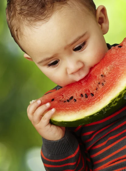 Portrét pohledný kluk drží kus melounu a suckin — Stock fotografie