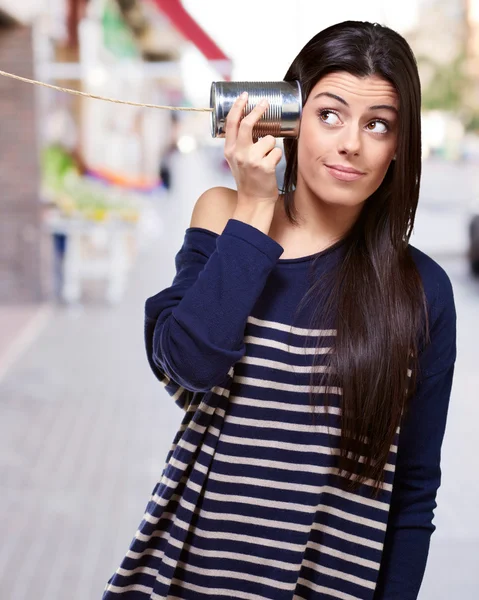 Porträt einer jungen Frau, die auf der Straße durch eine Blechdose hört — Stockfoto