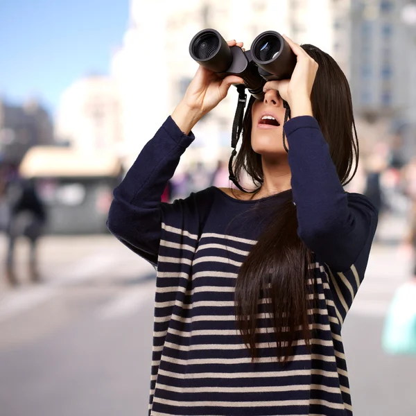 Retrato de una joven mirando a través de unos prismáticos en la ciudad — Foto de Stock