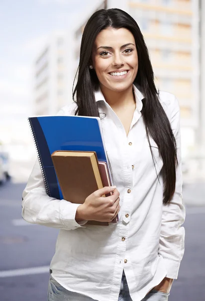 Bardzo młoda kobieta uśmiechając się i trzyma notebooki, odkryty — Zdjęcie stockowe