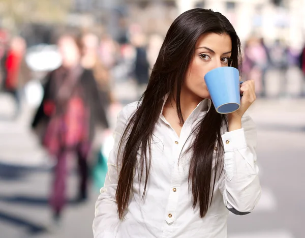 Portret van een jonge vrouw drinken op drukke stad — Stockfoto
