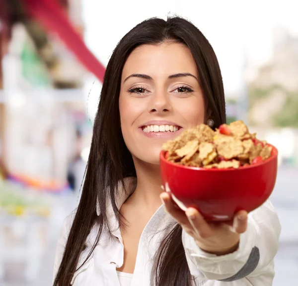 Retrato de mujer joven ofreciendo un tazón de cereales en la calle — Foto de Stock