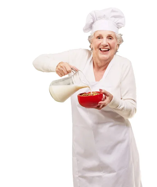 年配の女性が牛乳を注いで ロイヤリティフリーのストック写真