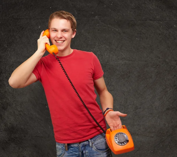 Portrait of young man talking with vintage telephone against a g Royalty Free Stock Photos