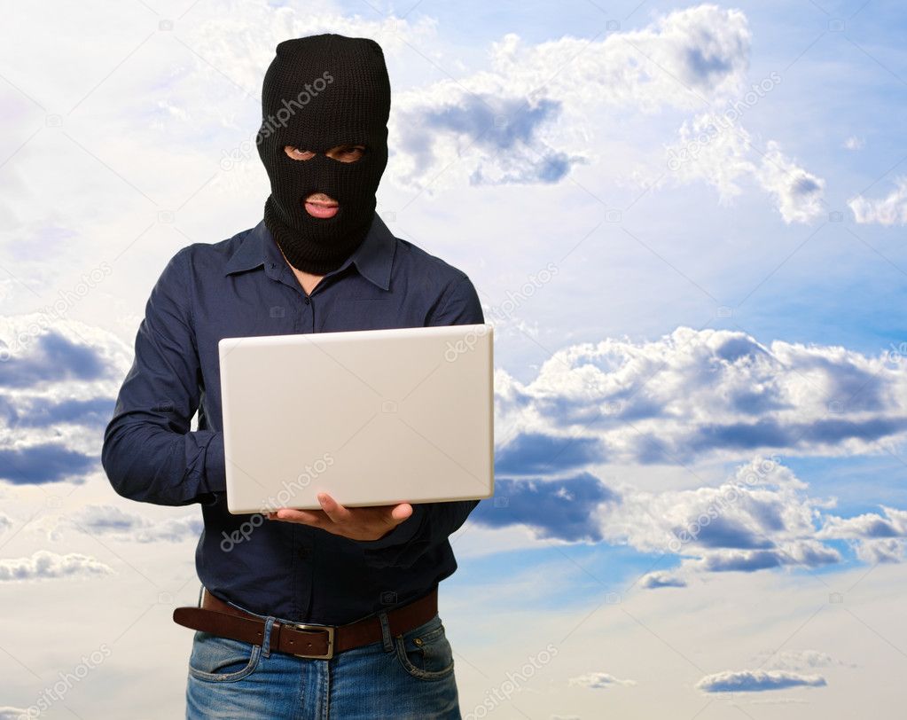 Young male thief holding laptop