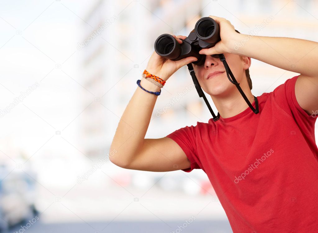 Portrait of young man with binoculars against a building