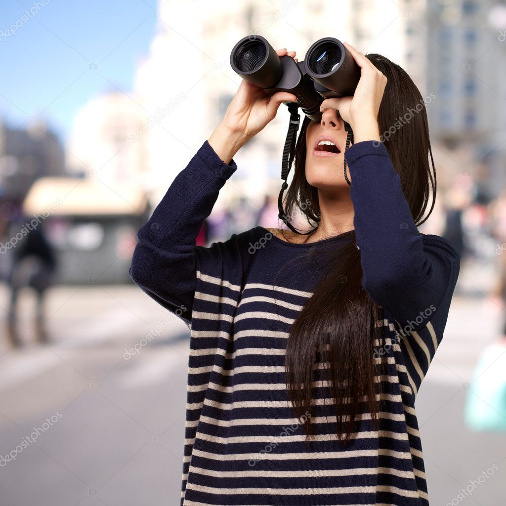 Portrait of young girl looking through a binoculars at city