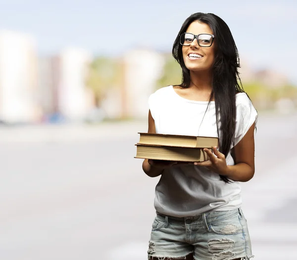 Retrato de una joven sosteniendo libros en una ciudad abarrotada — Foto de Stock