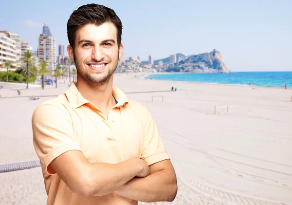 Portrait of a handsome young man standing against a beach — Stock Photo, Image
