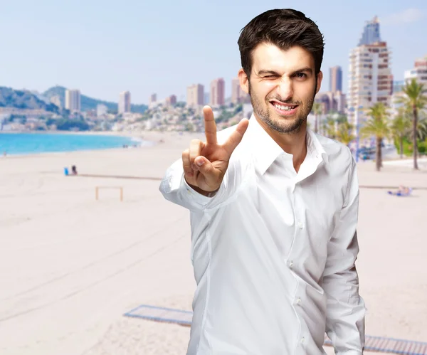 Portrait of a handsome young man doing victory symbol against a — Stock Photo, Image