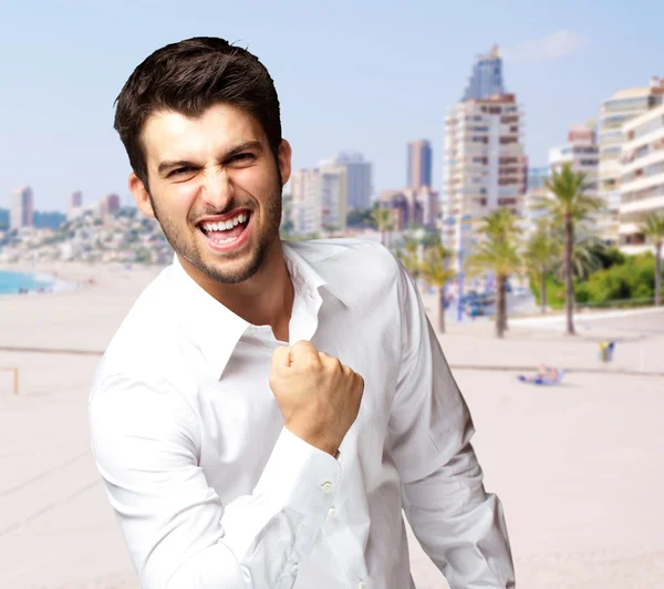Porträtt av framgångsrik ung man mot en strand — Stockfoto