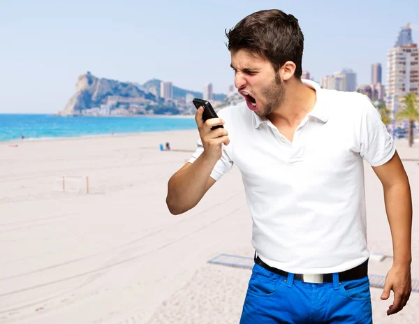 Retrato de un joven que discute contra una playa — Foto de Stock