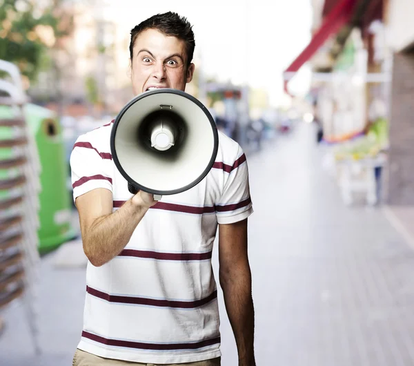 Портрет молодого человека, кричащего с мегафоном на улице — стоковое фото