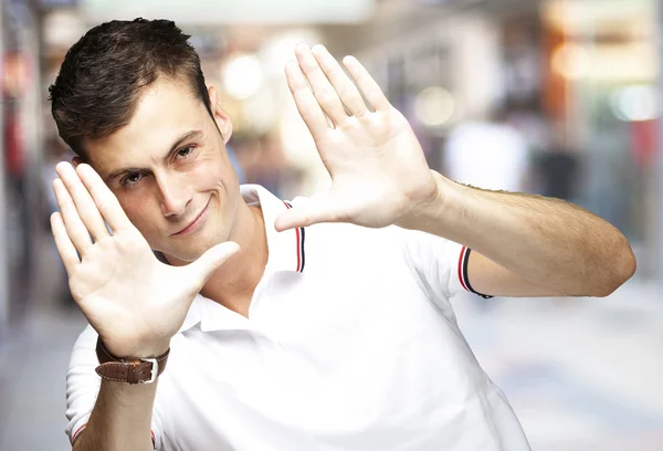 Portrait of young man doing photo gesture at a crowded place — Stock Photo, Image