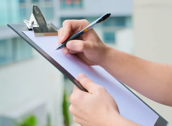 Businessman Holding A Clipboard And Writing — Stock Photo, Image