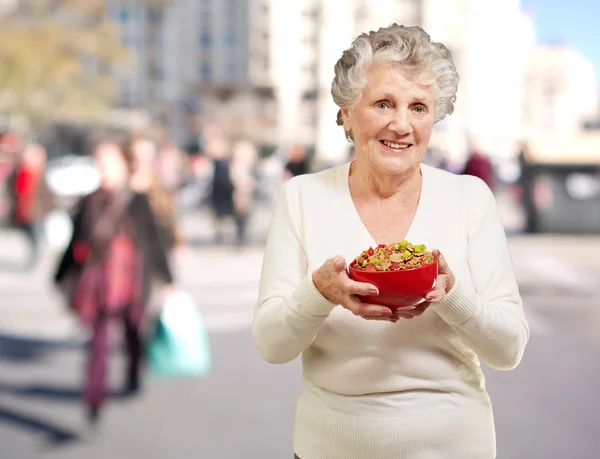 Retrato de mulher idosa saudável segurando tigela de cereais na rua — Fotografia de Stock