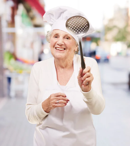 Portrét ženy milé vedoucí kuchař drží kovovou lžící na str — Stock fotografie