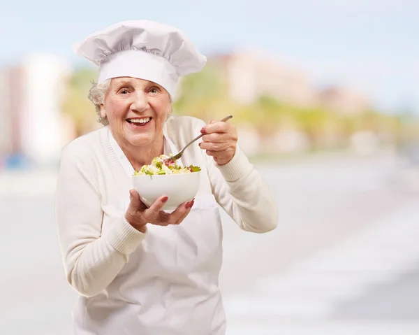 Retrato de cozinheira sênior comendo salada na cidade — Fotografia de Stock