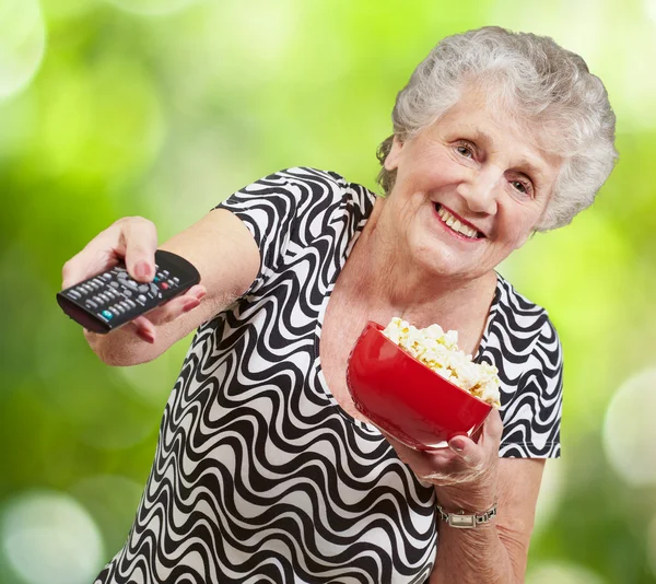 Портрет счастливой пожилой женщины, смотрящей телевизор на фоне природы — стоковое фото