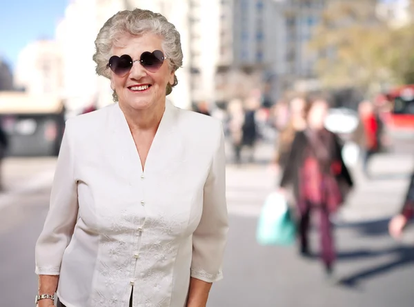 Portrét šťastný starší ženy nosí brýle srdce na ulici — Stock fotografie