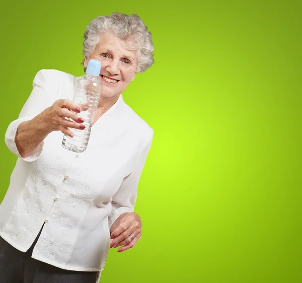 Portrait of healthy senior woman holding a water bottle over gre — Stock Photo, Image
