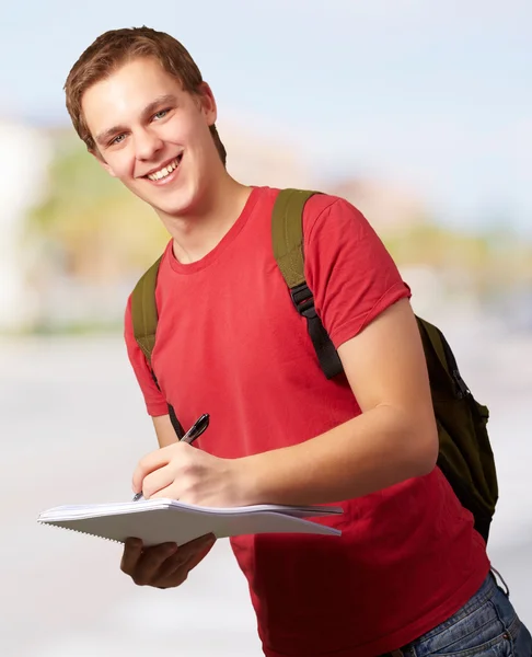 Πορτρέτο του ανθρώπου νεαρός φοιτητής, γράφει σε ένα σημειωματάριο στην οδό — Φωτογραφία Αρχείου